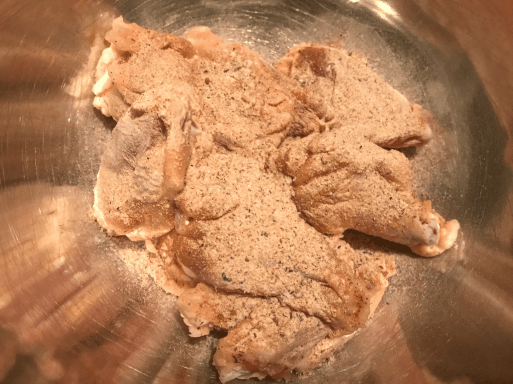 seasoning added to bowl of chicken wing pieces