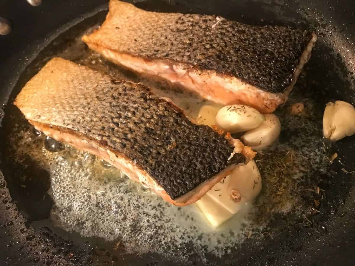 Salmon skin side up in hot pan with butter and thyme