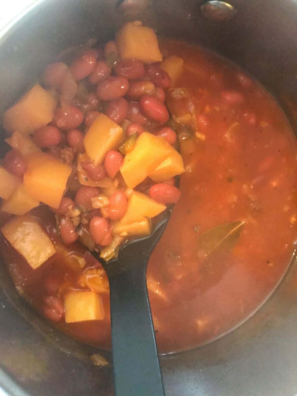 close up of Puerto Rican style red beans in pot scooped on a spoon