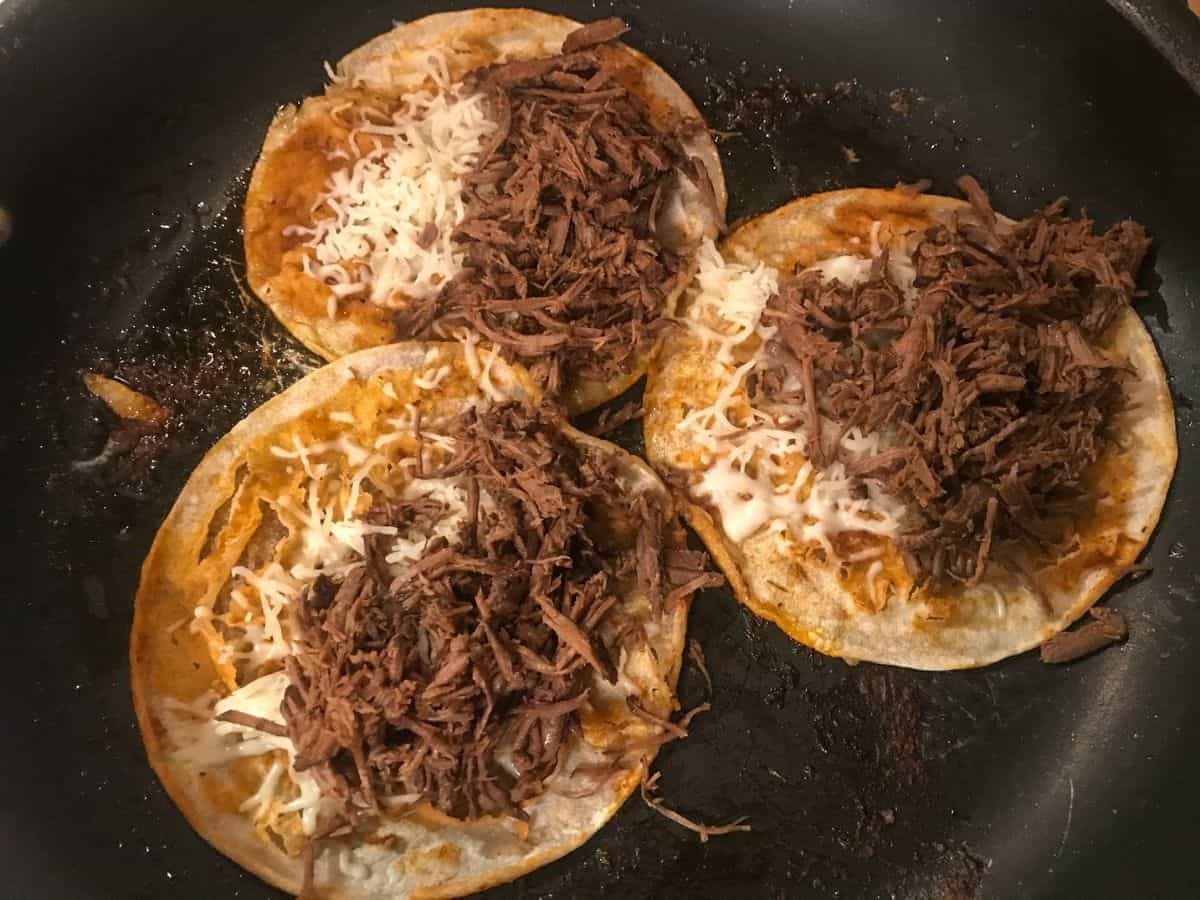 Corn tortillas topped with mozzarella cheese and shredded beef