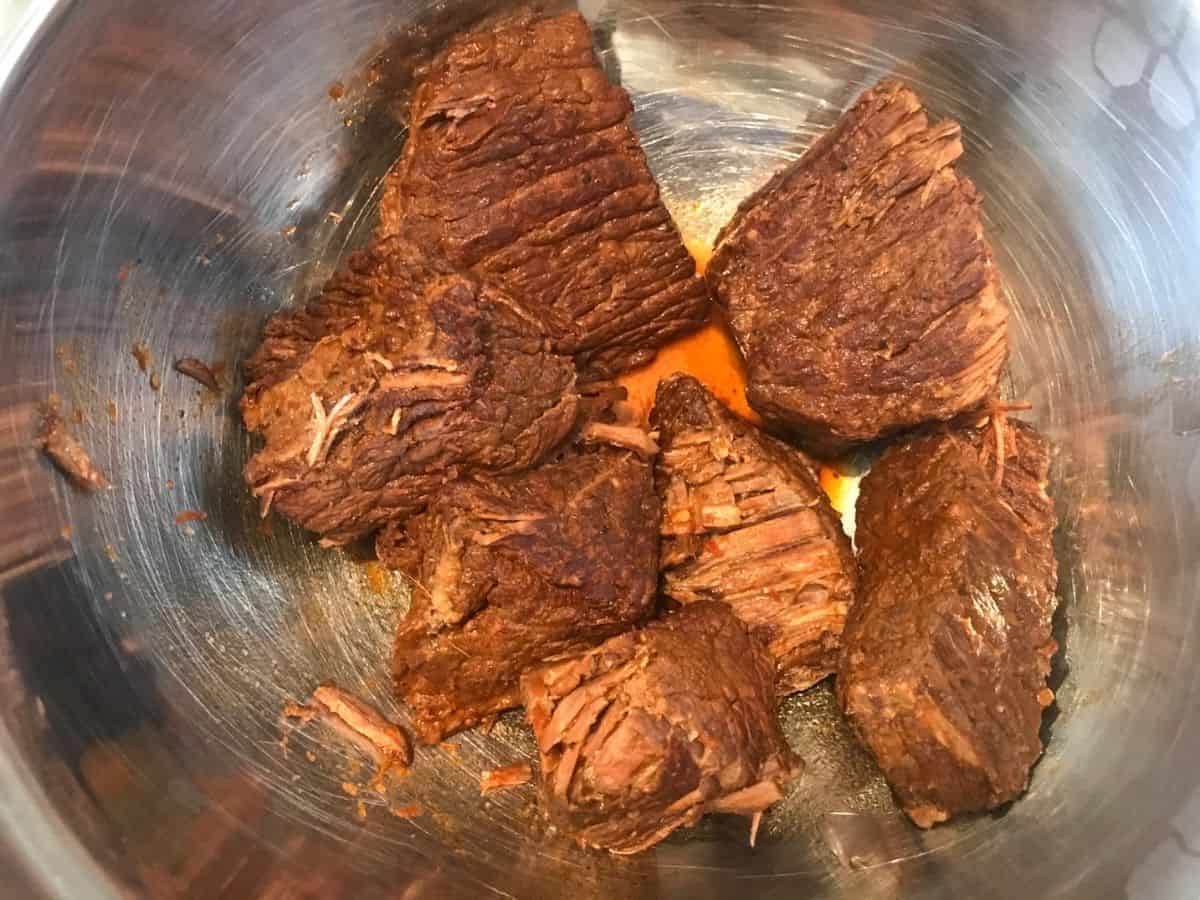 Cooked chunks of chuck roast in a mixing bowl