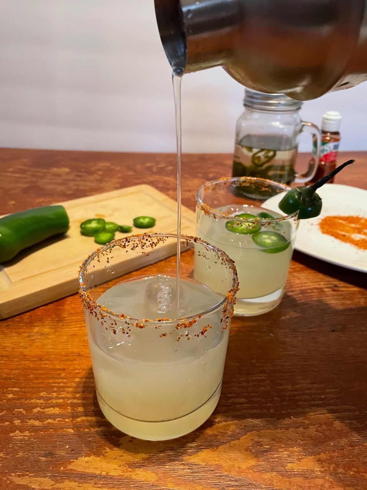 margarita being poured into Tajin rimmed glass from cocktail shaker
