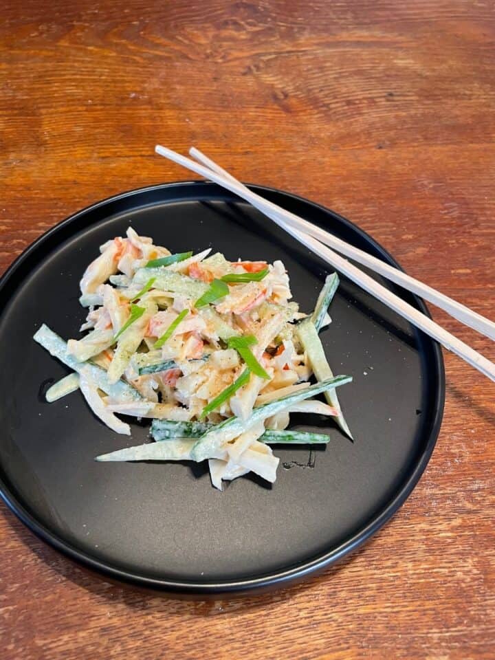 Spicy Kani Salad served on a black plate with chopsticks
