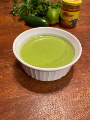 bowl of peruvian green sauce with ingredients in background