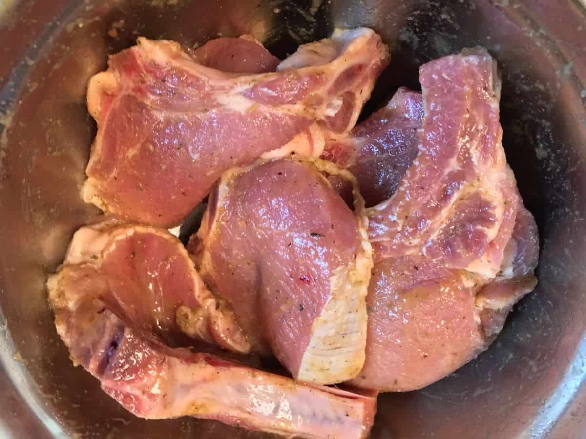pork chops coated in marinade in a mixing bowl