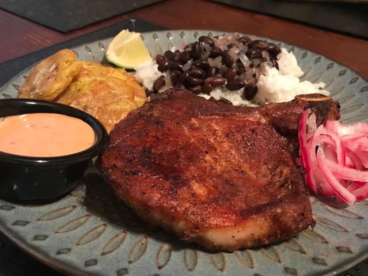 Puerto Rican pork chops served with rice, beans, tostones, and red onion.