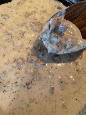 close up of sausage gravy being spooned from pan
