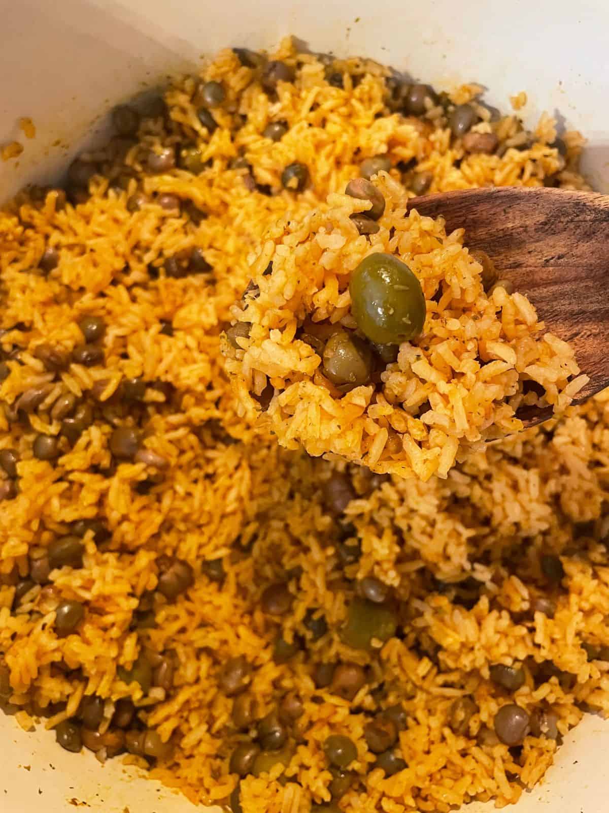 close up of a spoonful of arroz con gandules over pot