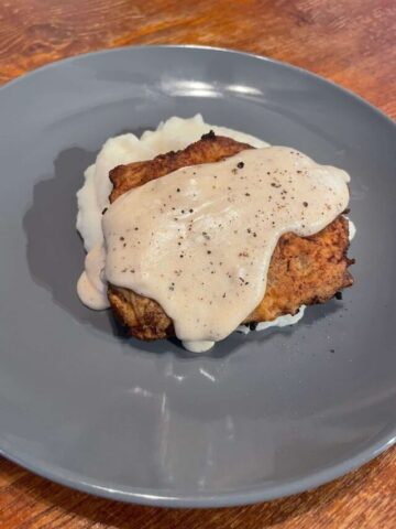 chicken fried steak served with white gravy on top with a side of mashed potatoes