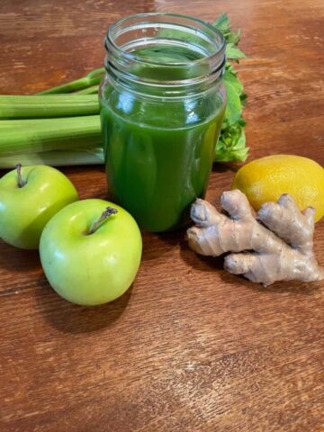 mason jar of green juice with ingredients around glass