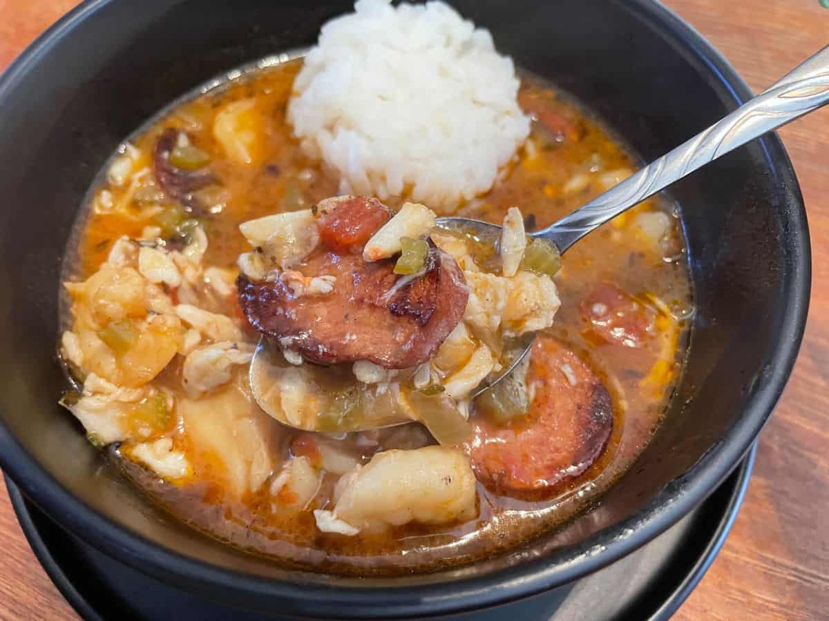 a spoonful of gumbo held over a bowl of gumbo