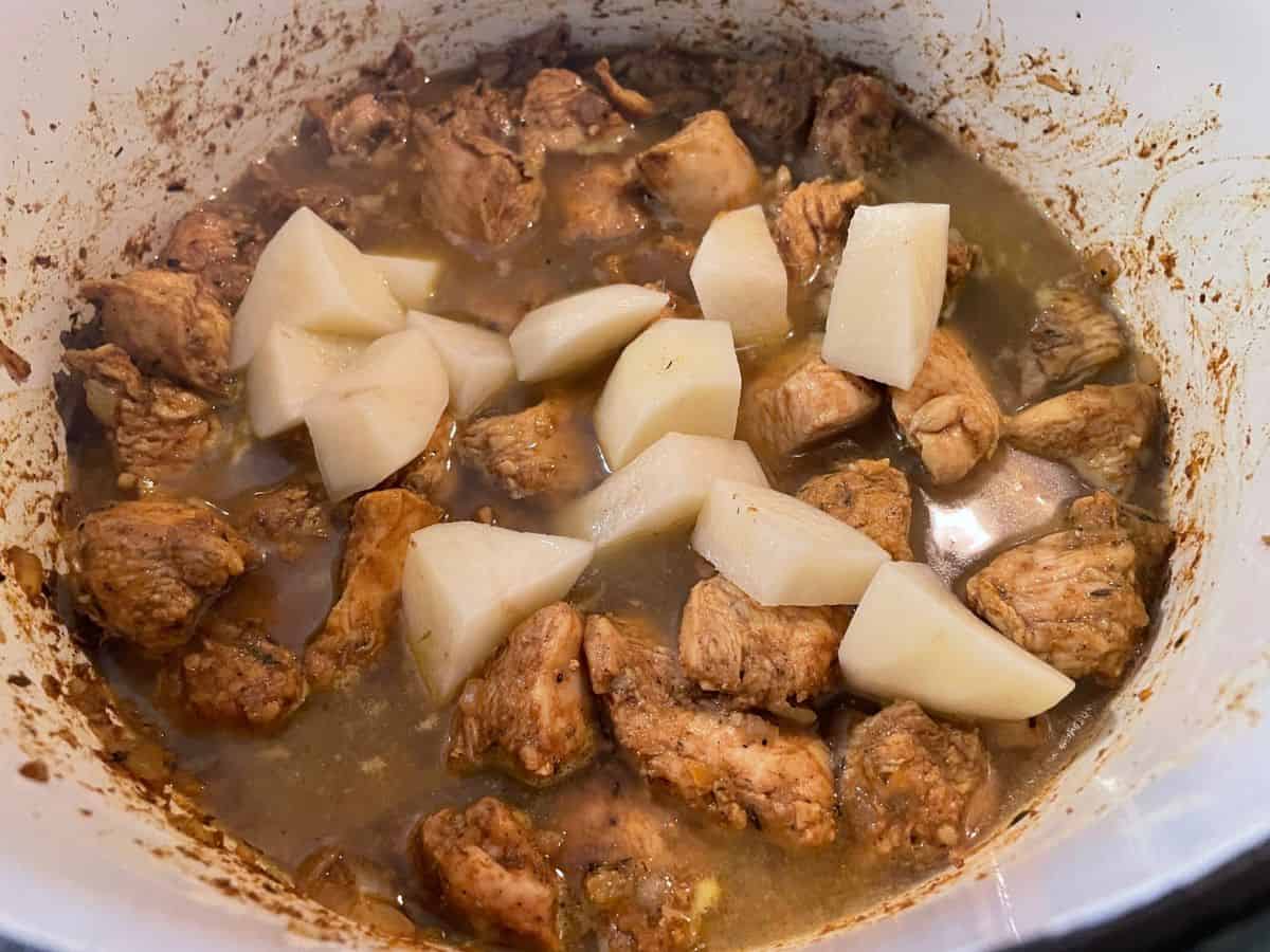 water and potatoes added to dutch oven of curry chicken