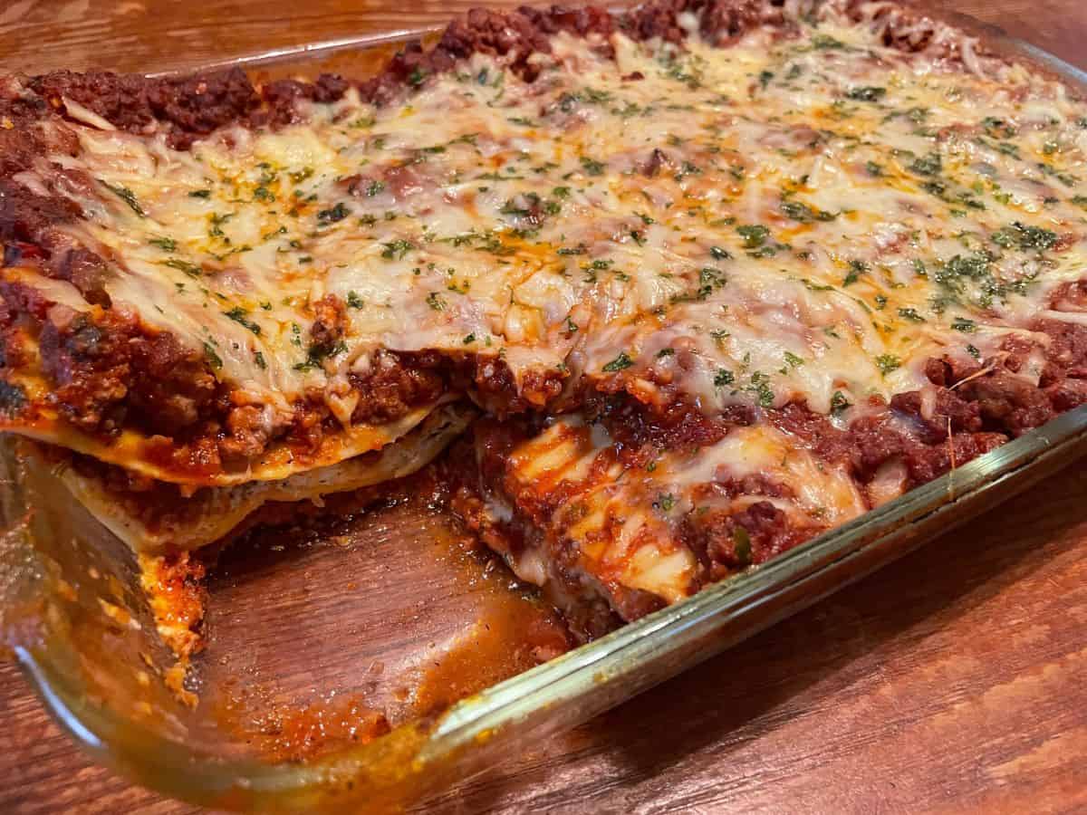 lasagna with a piece cut out of casserole dish