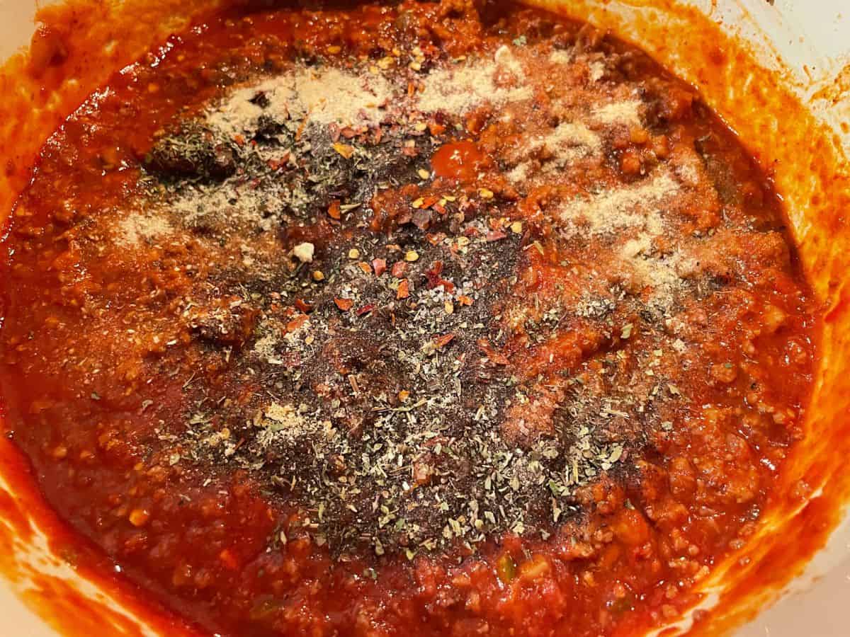 pasta sauce simmering with seasonings sprinkled on top