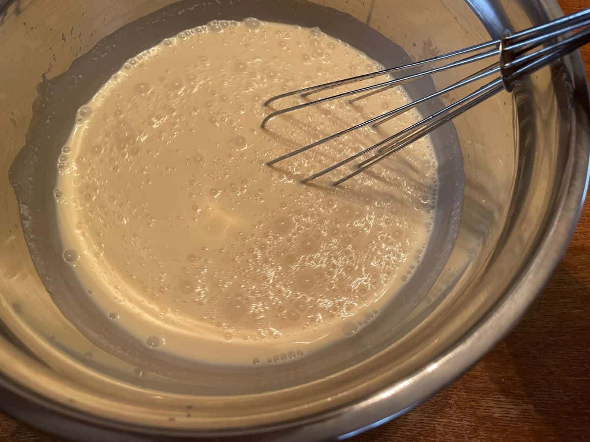 milk mixture in a mixing bowl with a whisk