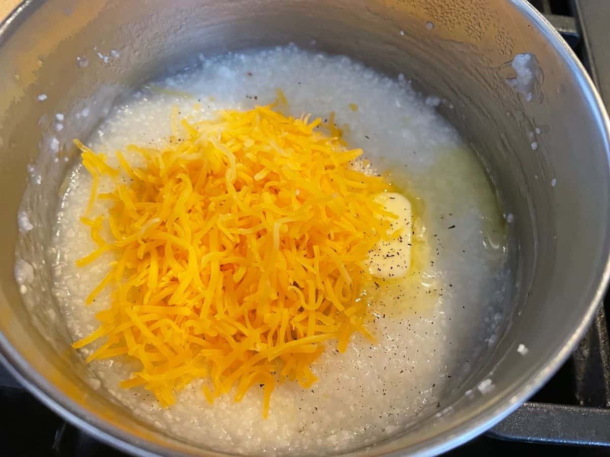 mall pot with cooked grits, butter, salt, pepper, and shredded cheese.