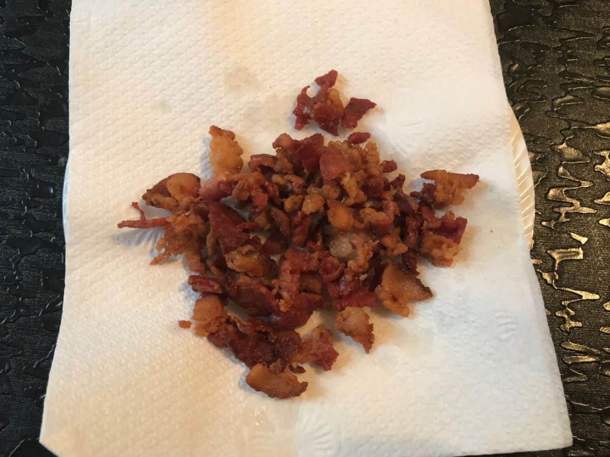 small pieces of cooked bacon draining on a paper towel