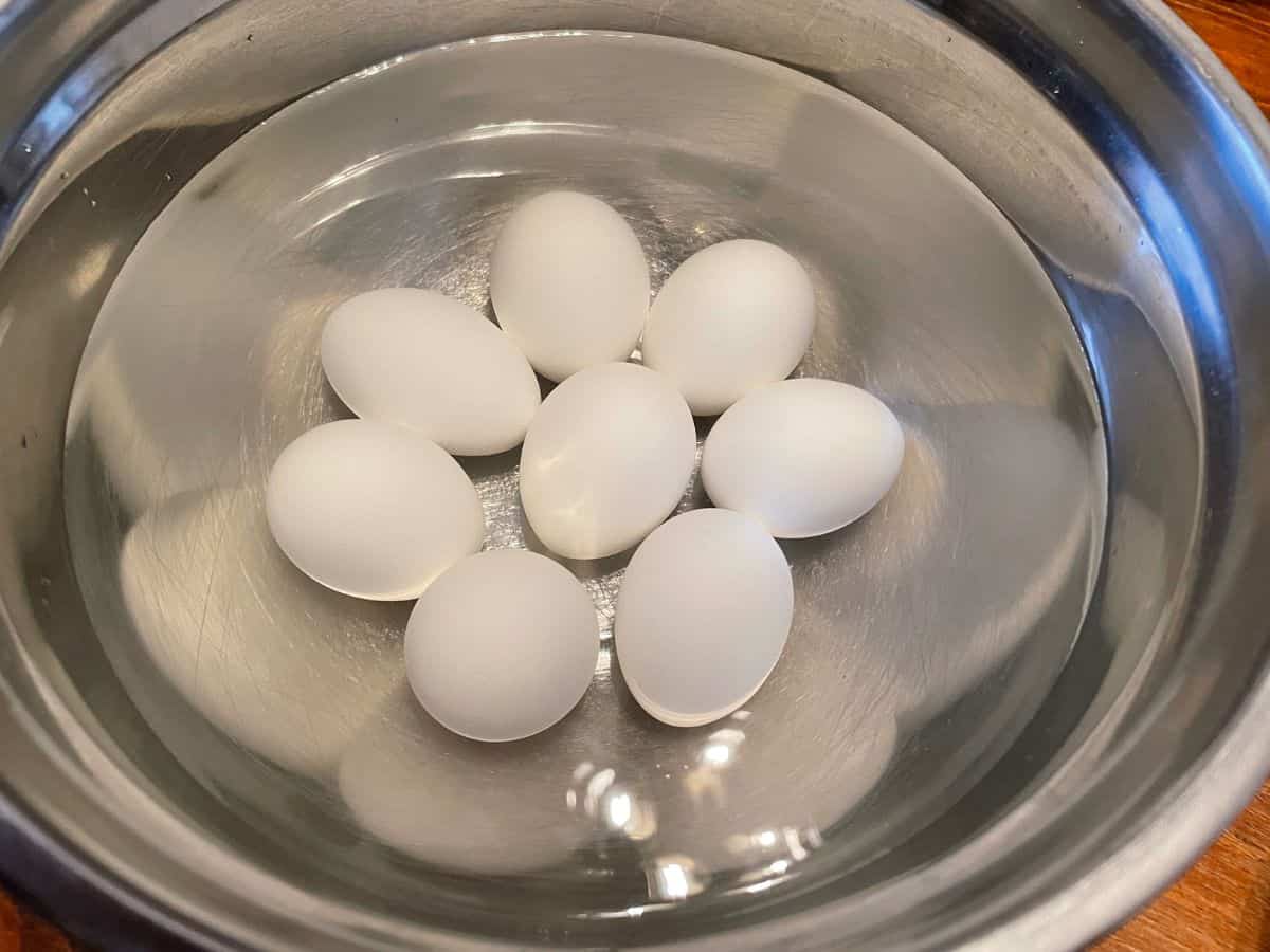 Hard boiled eggs cooling in a large bowl of cold water