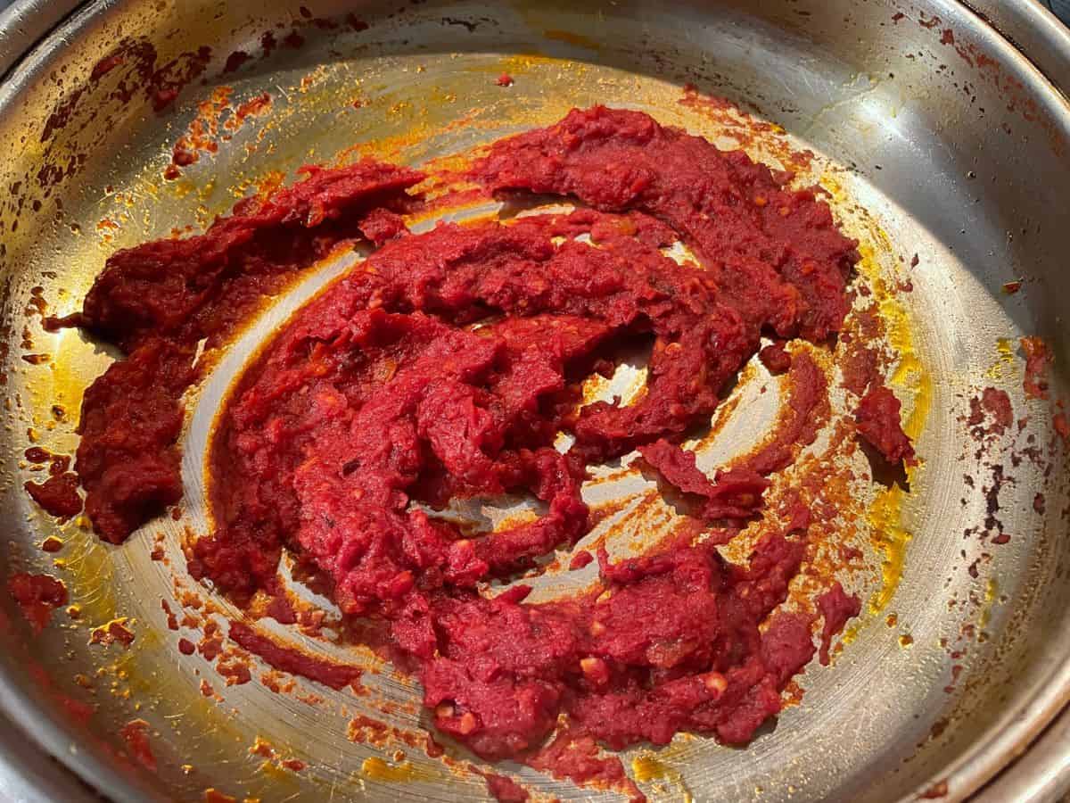 tomato paste cooking in pan with chilis and aromatics
