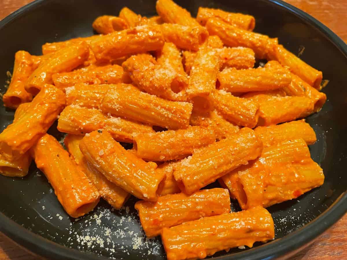 close up of spicy rigatoni served with grated parmesan cheese on top