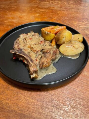 served smothered pork chops with vegetables on a black plate