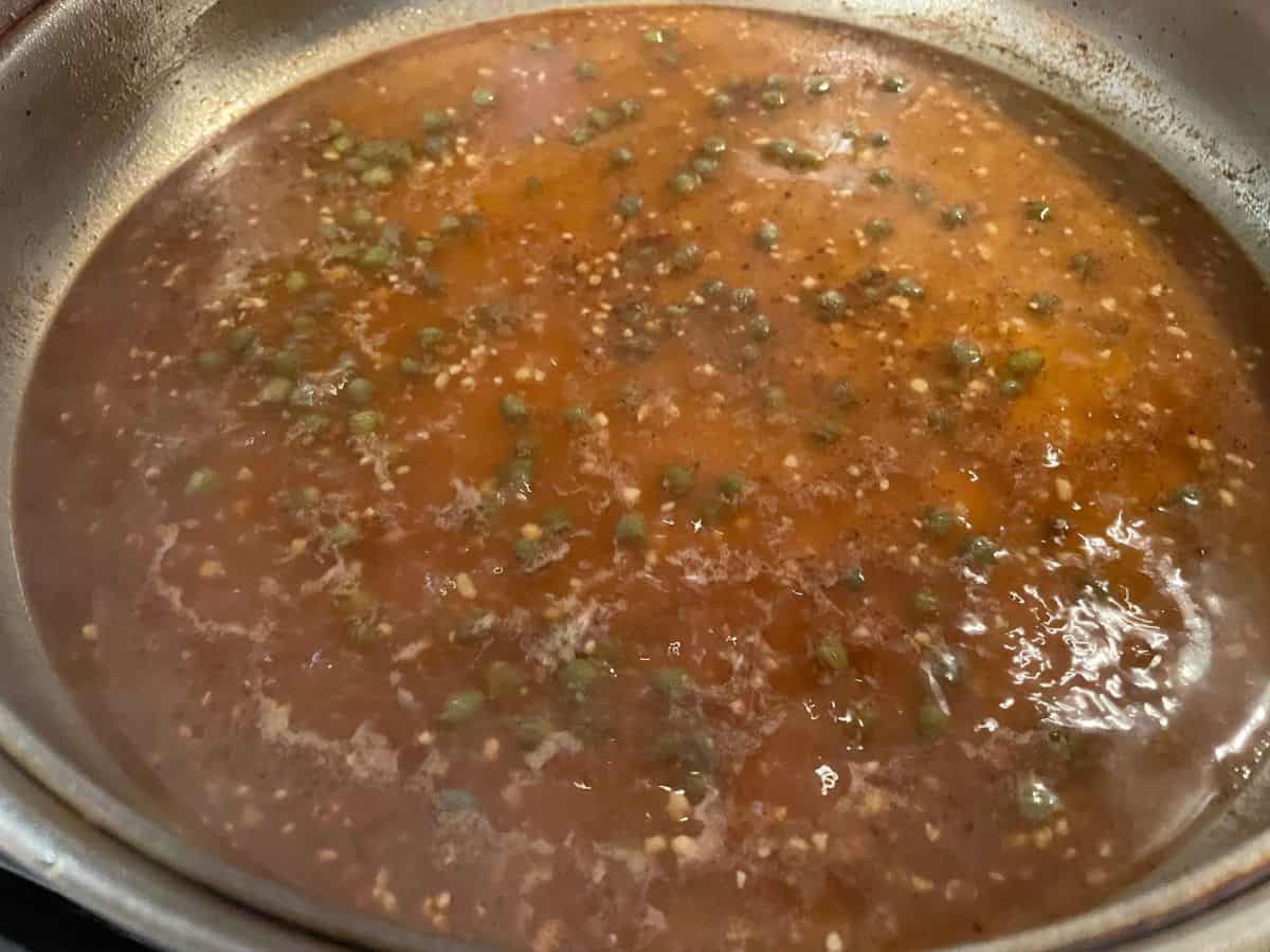chicken piccata sauce simmering in skillet