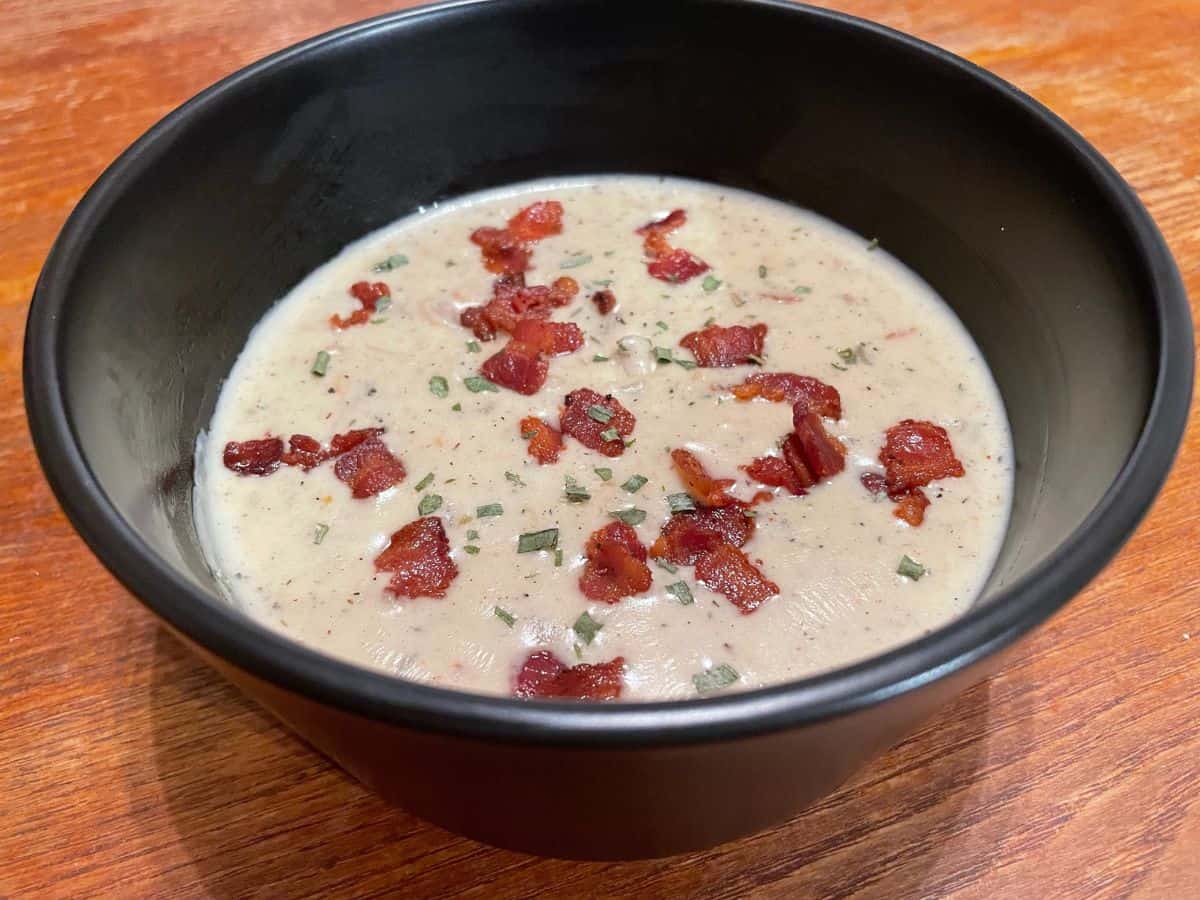 bowl of clam chowder garnished with chopped bacon and chives